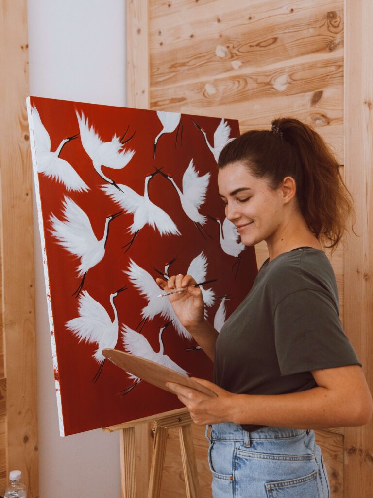 Woman smiling and feeling good as she paints birds in flight.