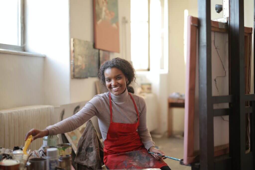 Woman smiling while doing what she loves: painting.